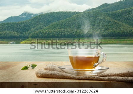 Tea cup with burlap on the wooden table and the swamp background