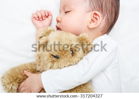 Baby sleeping with her teddy bear, new family and love concept (Soft focus and blurry)