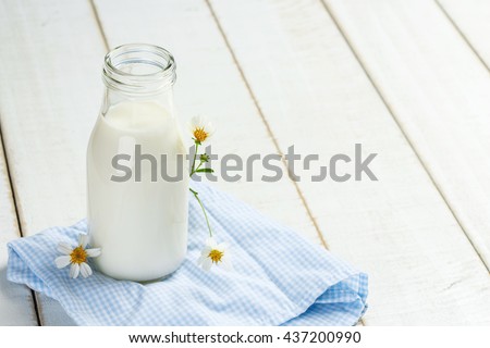 A bottle of milk on a white wooden table on a blue background, tasty, nutritious and healthy dairy products
