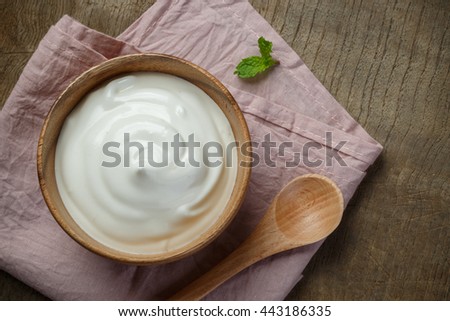 Yogurt in wooden bowl on wooden background with pink cotton and wooden spoon. plain yoghurt. yogurt. yoghurt.