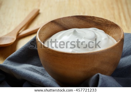 Yogurt in wooden bowl on wooden background with blue cotton and wooden spoon. plain yoghurt. yogurt. yoghurt.