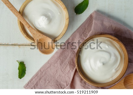 Yogurt in wooden bowl on wooden background with pink cotton and wooden spoon. plain yoghurt. yogurt. yoghurt.
