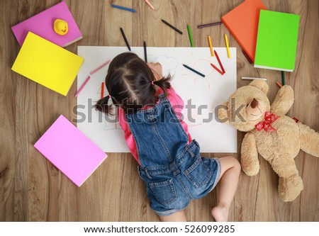 Adorable little girl drawing artwork. Studio shot top view of child on floor