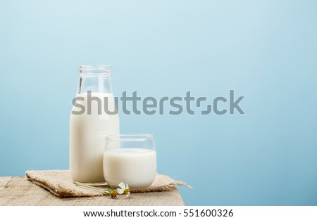 A bottle of rustic milk and glass of milk on a wooden table on a blue background, tasty, nutritious and healthy dairy products