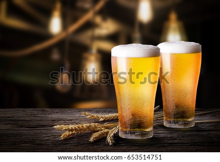 Glasses of light beer with barley at bar. Two glass of beer with wheat on wooden table