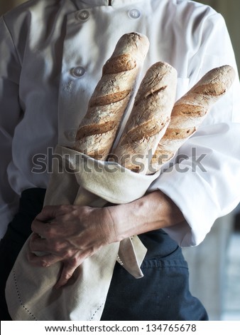 Female baker holding fresh baked French baguette