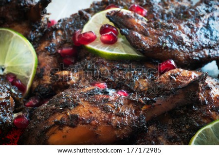 Platter of roasted chicken with jerk sauce, pomegranate,  lime and herb garnish
