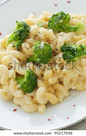 White plate of fresh homemade macaroni and cheese with broccoli and red pepper