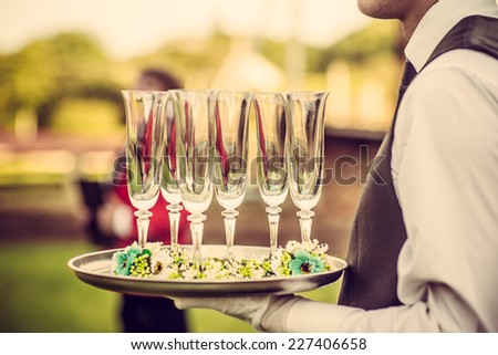 Waiter with glasses on the tray at wedding ceremony, waiting for champagne