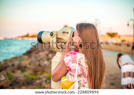Girl with monocular looking at the evening sea landscape