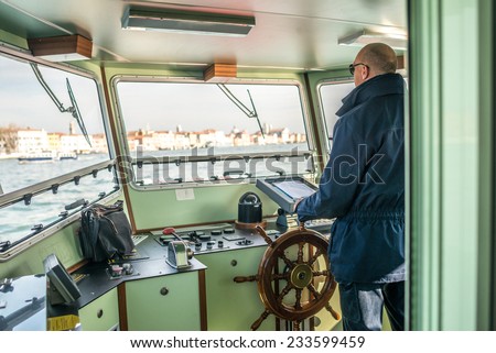 Man driving the boat, photo behind the driver in the cabin