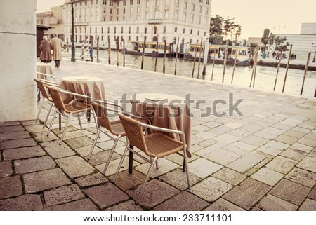 Empty cafe tables outdoor near river in Venice, Italy