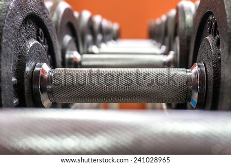 Line of dumbbells in the gym on orange background