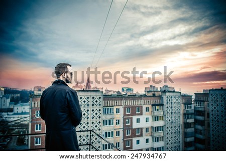 Man with beard on the top of the high building with cityscape on background