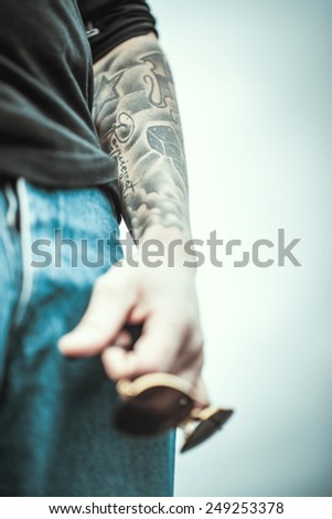 Man with tattoo on the top of the high building with cityscape on background