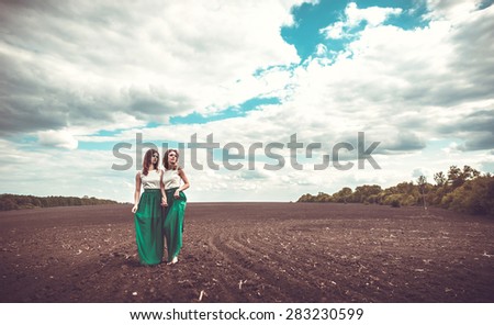 Two pretty girls in the yellow field in embroidery shirts