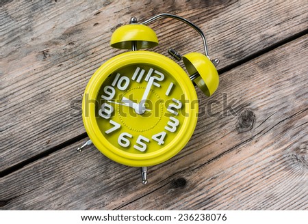 Yellow Alarm Clock at 9 O\'Clock on Wood Background
