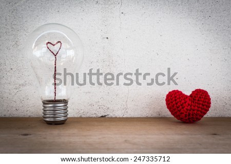 Lightbulb with Heart Shaped Filament and Red Heart Shaped Silk on Wood Floor and White Background