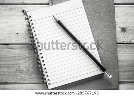 notebook and pencil on wood table ( black and white style )