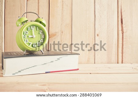clock and dictionary on wooden table over wood background, Still life style
