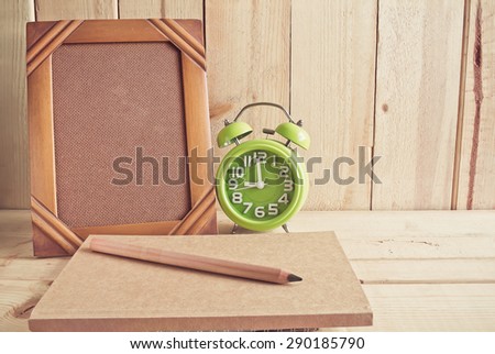 Old photo frame , notebook , clock and pencil on wooden table over wood background, Still life style