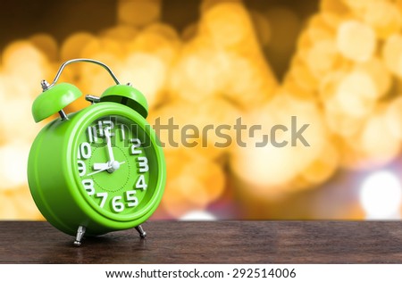 Clock on Wooden Floor with Yellow Bokeh Background