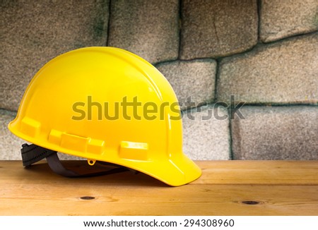 Yellow Safety Helmet on Wooden Floor with Stone Wall Background , color pop tone