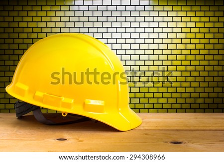 Yellow Safety Helmet on Wooden Floor with Brick Wall Background, color pop tone