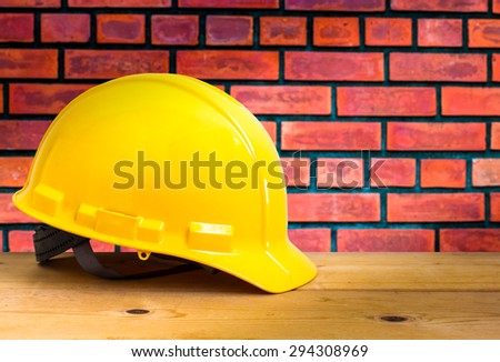 Yellow Safety Helmet on Wooden Floor with Brick Wall Background , color pop tone