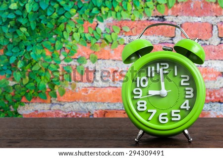 Clock on Wooden Floor with Plant and Brick Wall Background