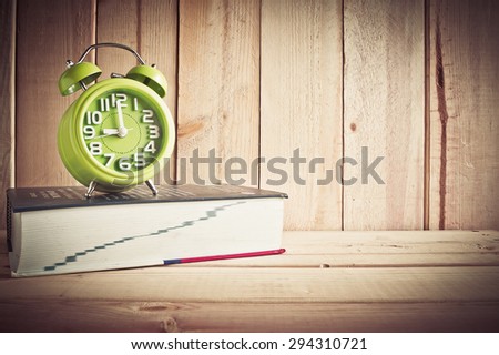 clock and dictionary on wooden table over wood background, Still life style