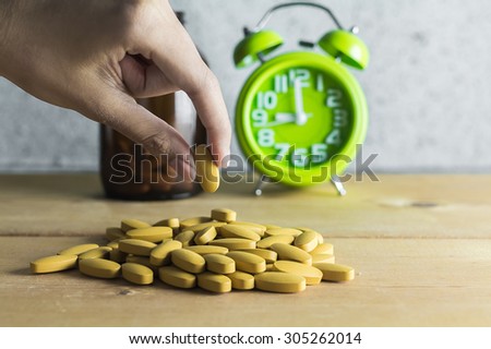 Hand pick a medicine on wood background