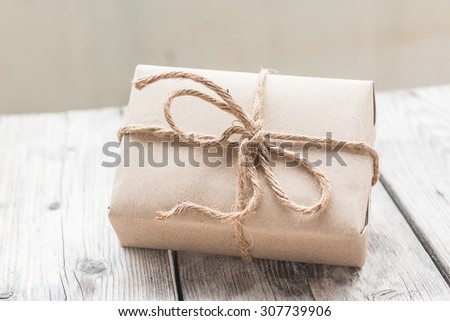 Vintage gift box brown paper wrapped with rope on wood background