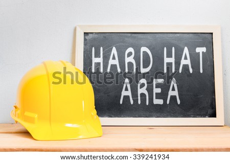 Helmet safety with chalkboard ( HARD HAT AREA ) on wood table , Safety First Concept