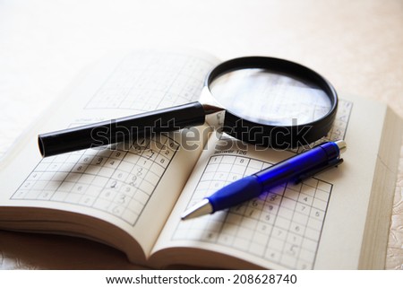 Scenery of Puzzle book, magnifying glass and pen on table