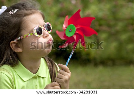 A cute child blowing a wind mill.