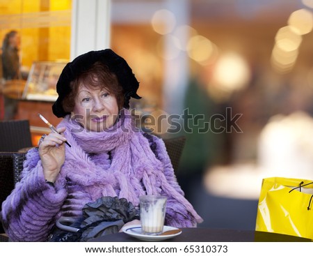 cheerful old Woman drinking coffee and smoking by Shopping slight pause