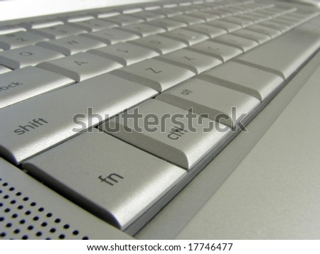 Closeup of a silver keyboard showing some symbols and letters.
