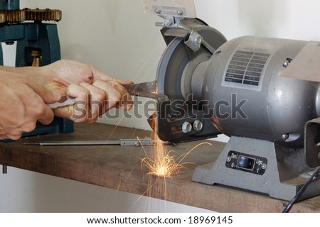 A worker grinding metal rod with sparks flying.