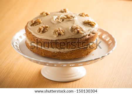 Beautifully presented Coffee and Walnut cake on a white cake stand