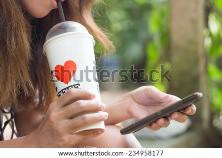 women drink ice coffee and use smart phone mobile outdoor