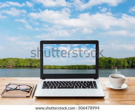laptop computer and coffee on wood workspace and mangrove forest background