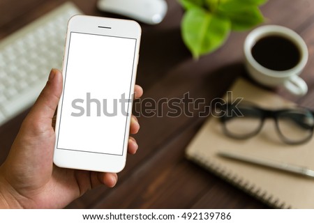 close up hand holding phone over work table, mockup smartphone blank screen for app screen adjustment