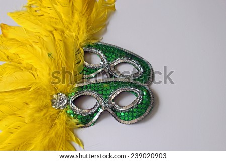 Green masks with yellow feathers symbolizing New Year\'s Eve parties, celebrations and disguise with white copy space on the right hand side