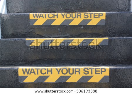 Yellow and black warning sign on stairs stating 