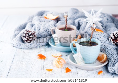 Traditional winter beverage tea with mint and tangerine. Christmas drink. Gray background with knitted scarf