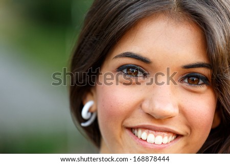 Closeup of a beautiful brunette girl with brown eyes smiling
