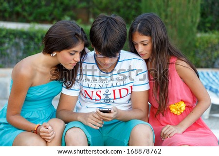 the boy playing with the phone while the girls watch making
