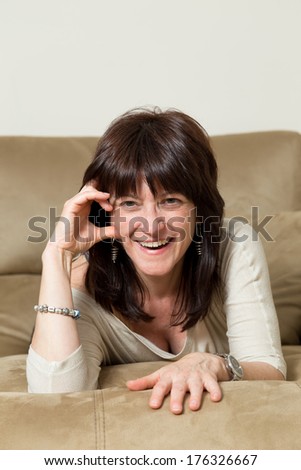woman laughing at the camera while she lies on the couch