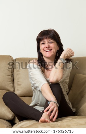 woman sitting on a couch laughing abietamente, happy person